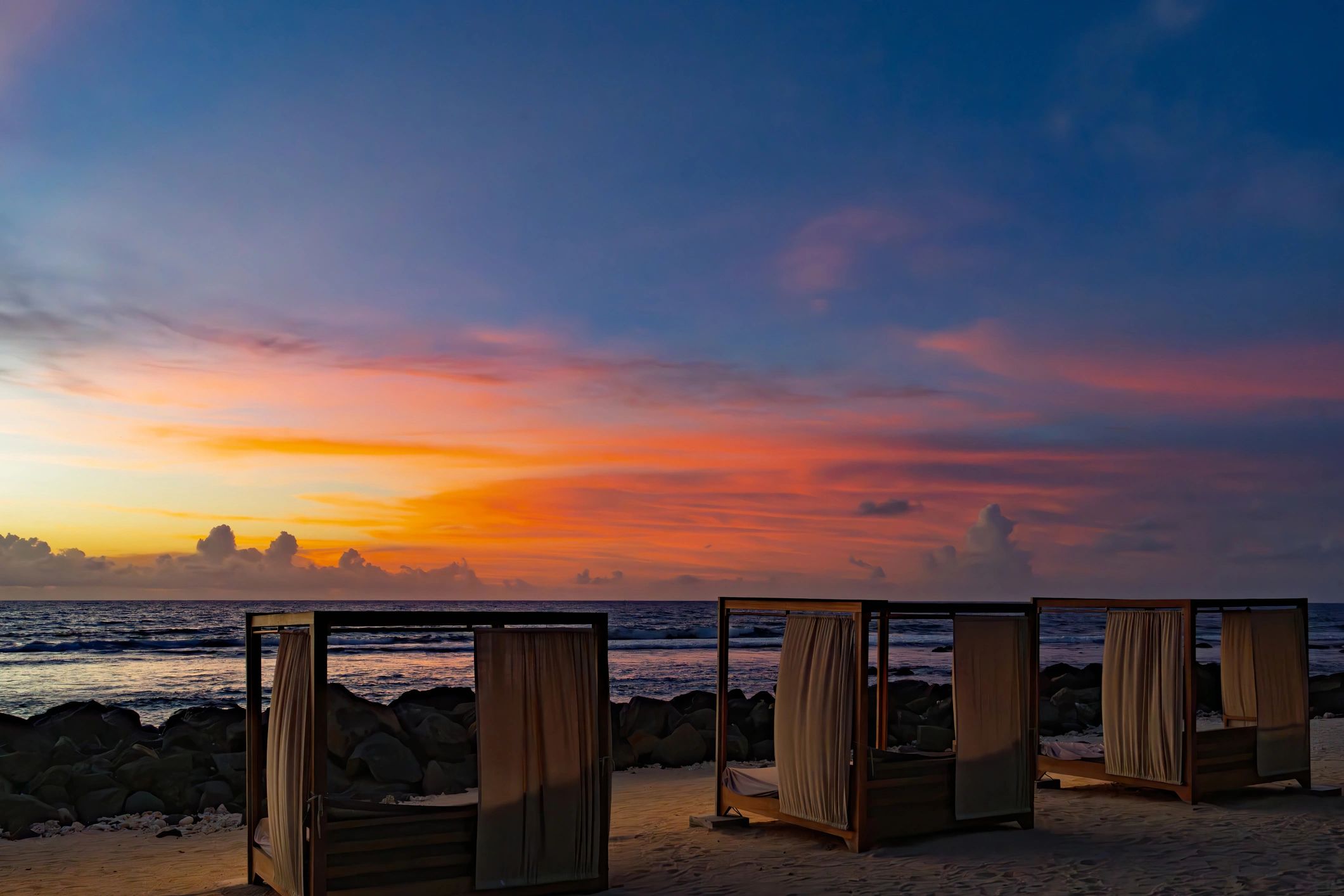 Luxury beach cabanas at sunset overlooking the ocean