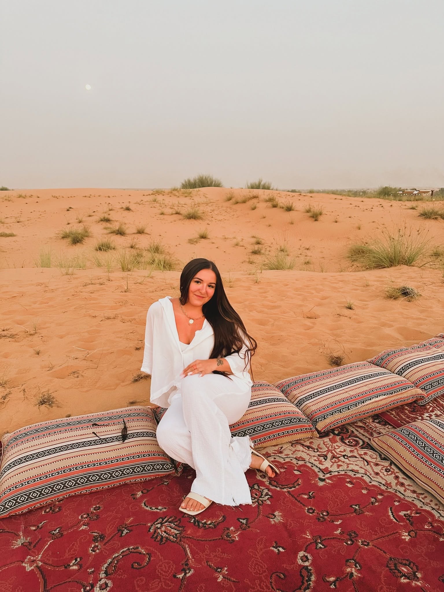 Courtney seated outdoors in a desert setting, smiling at the camera