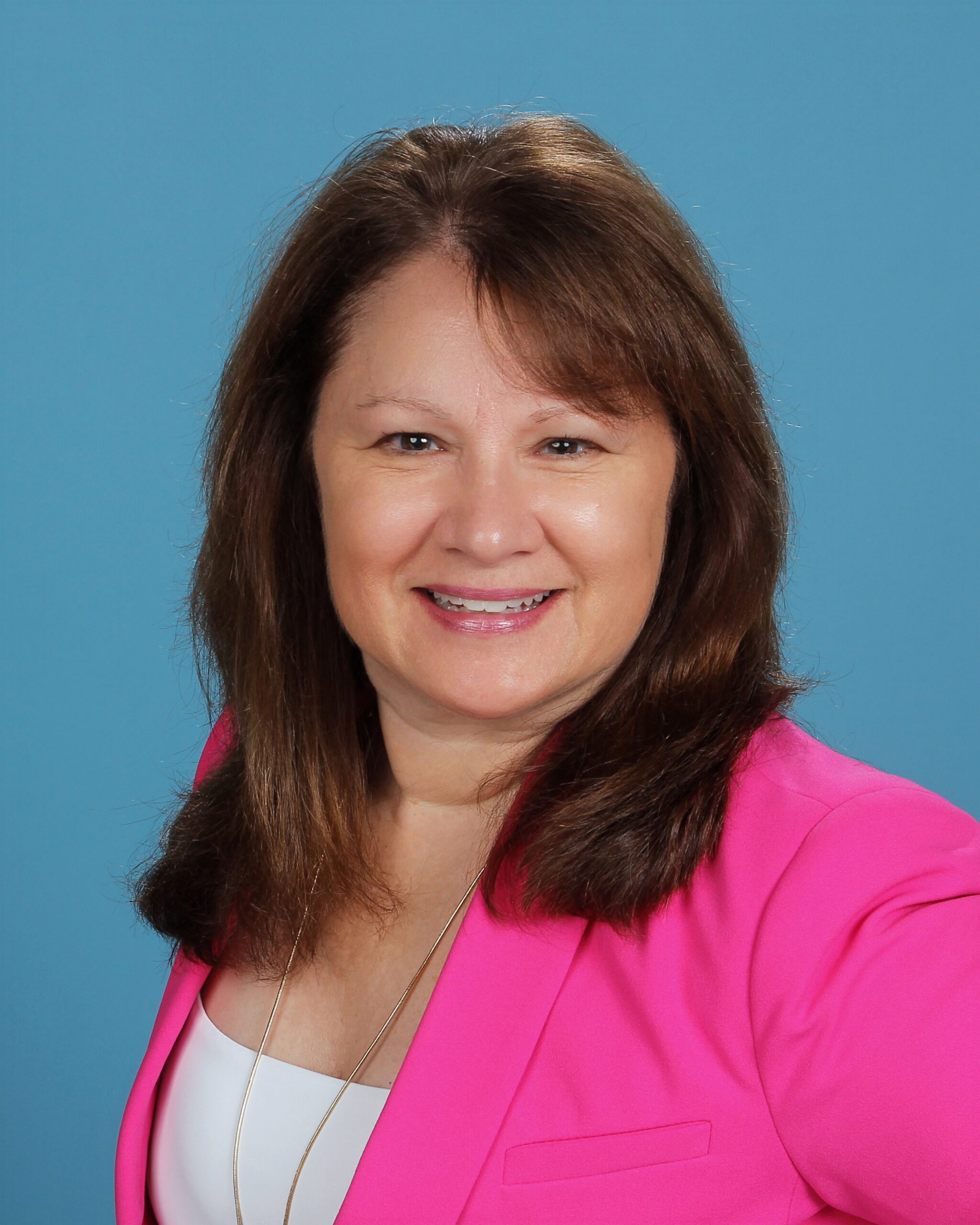 Tamara Borello smiling in a pink blazer against a light blue background